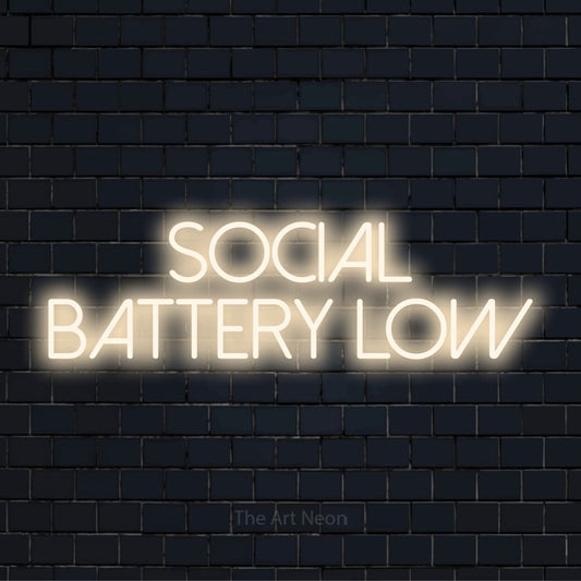 "Social Battery Low" glowing LED neon sign on a black brick wall