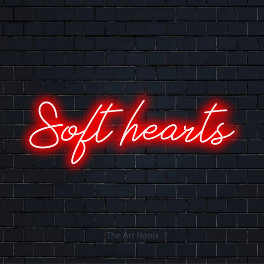 "Soft Hearts" glowing LED neon sign on a black brick wall