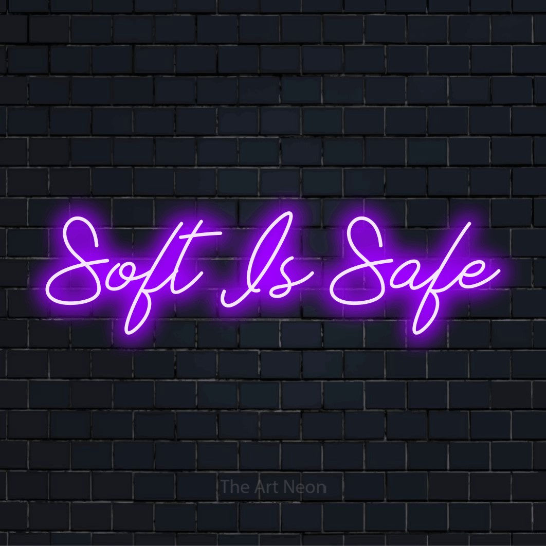 "Soft Is Safe" script-style LED neon sign on a black brick wall