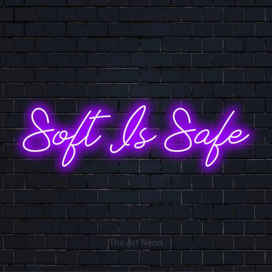 "Soft Is Safe" script-style LED neon sign on a black brick wall