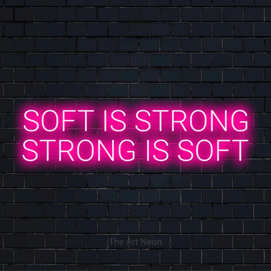 "Soft Is Strong Strong Is Soft" LED neon sign on a black brick wall