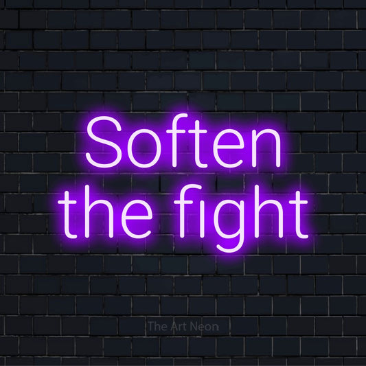 "Soften The Fight" neon text design on a black brick wall