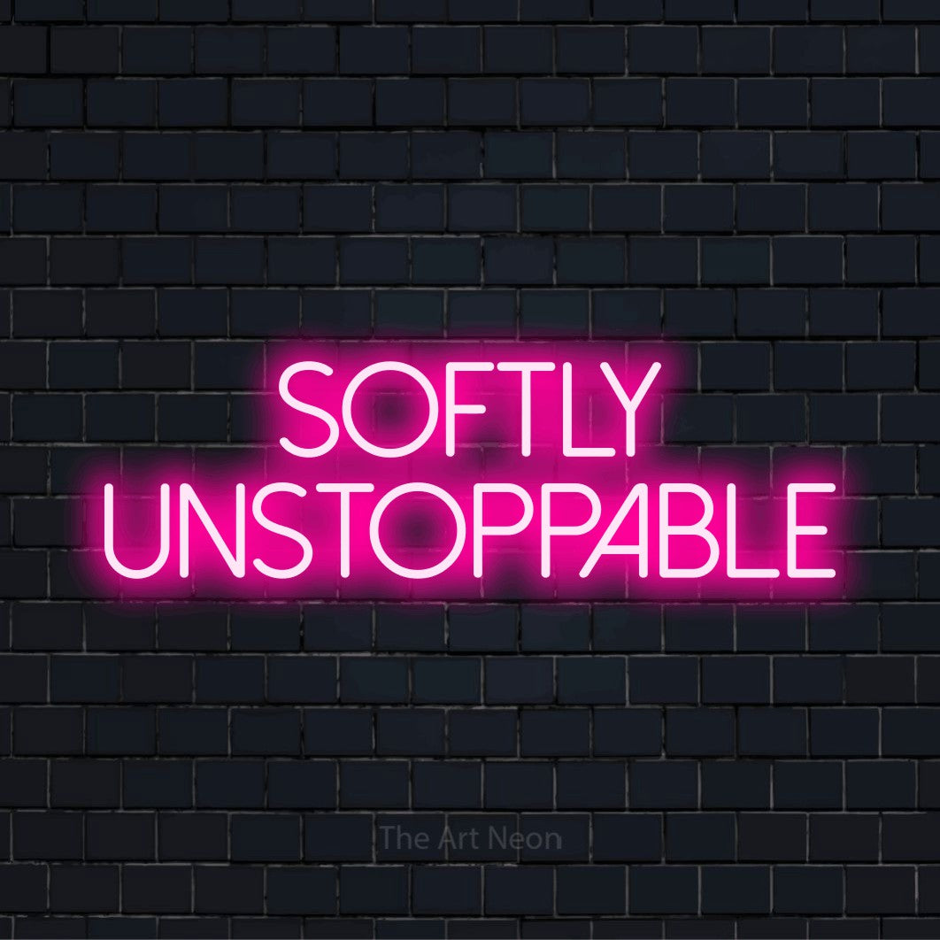 "Softly Unstoppable" LED neon sign on a black brick wall