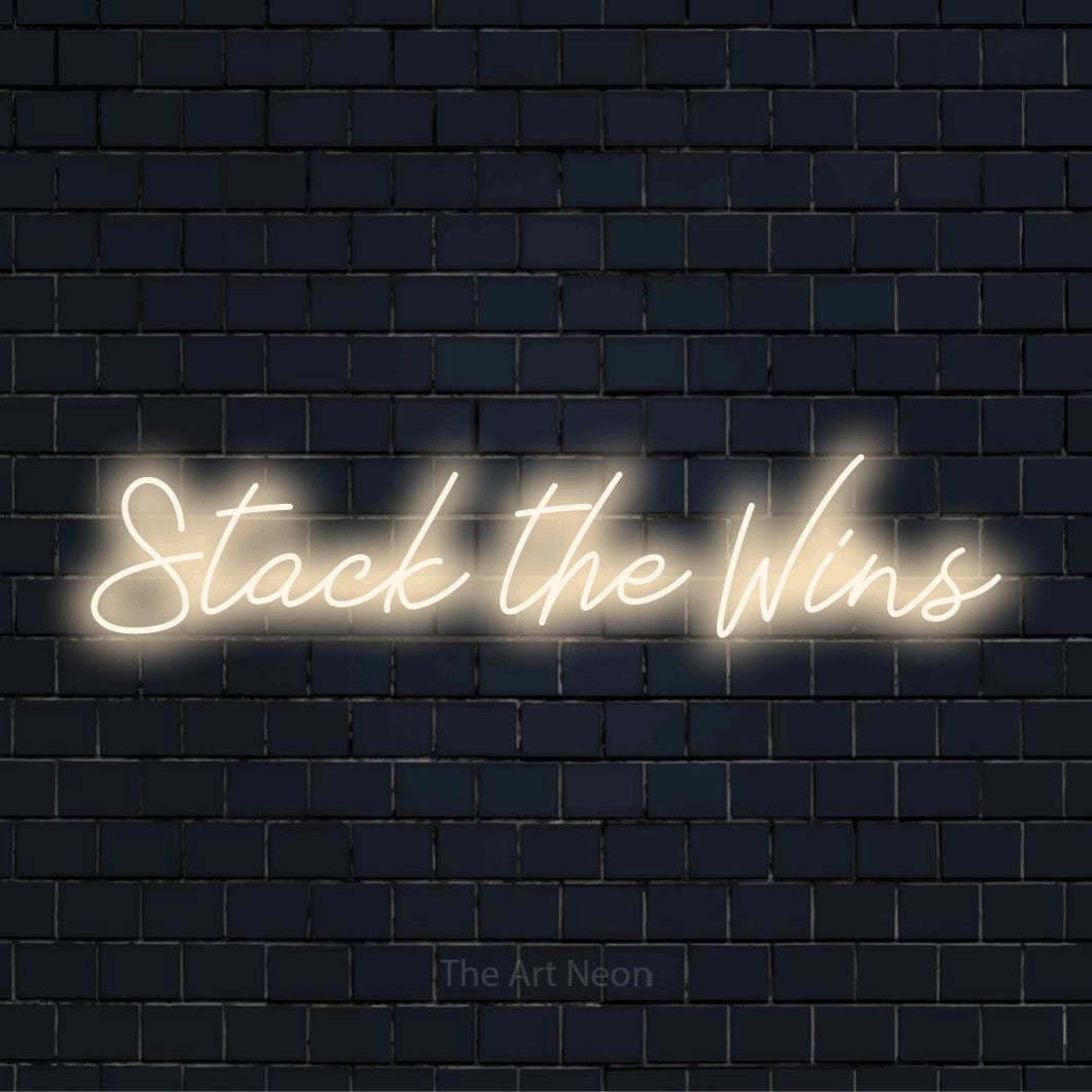 "Stack The Wins" text design with neon effect on a black brick wall