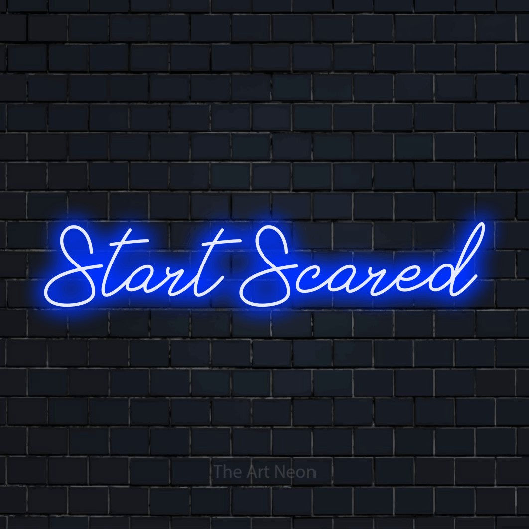 "Start Scared" script-style LED neon sign on a black brick wall