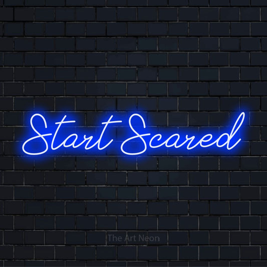 "Start Scared" script-style LED neon sign on a black brick wall