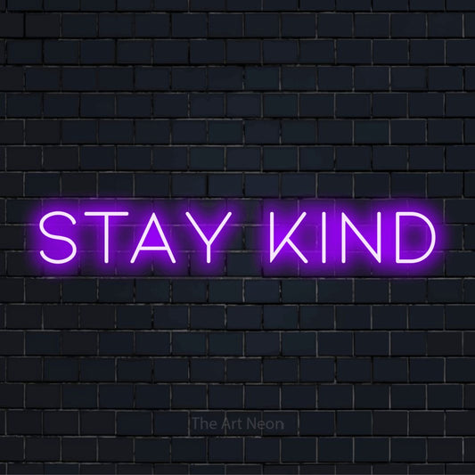 "Stay Kind" neon text design on a black brick wall