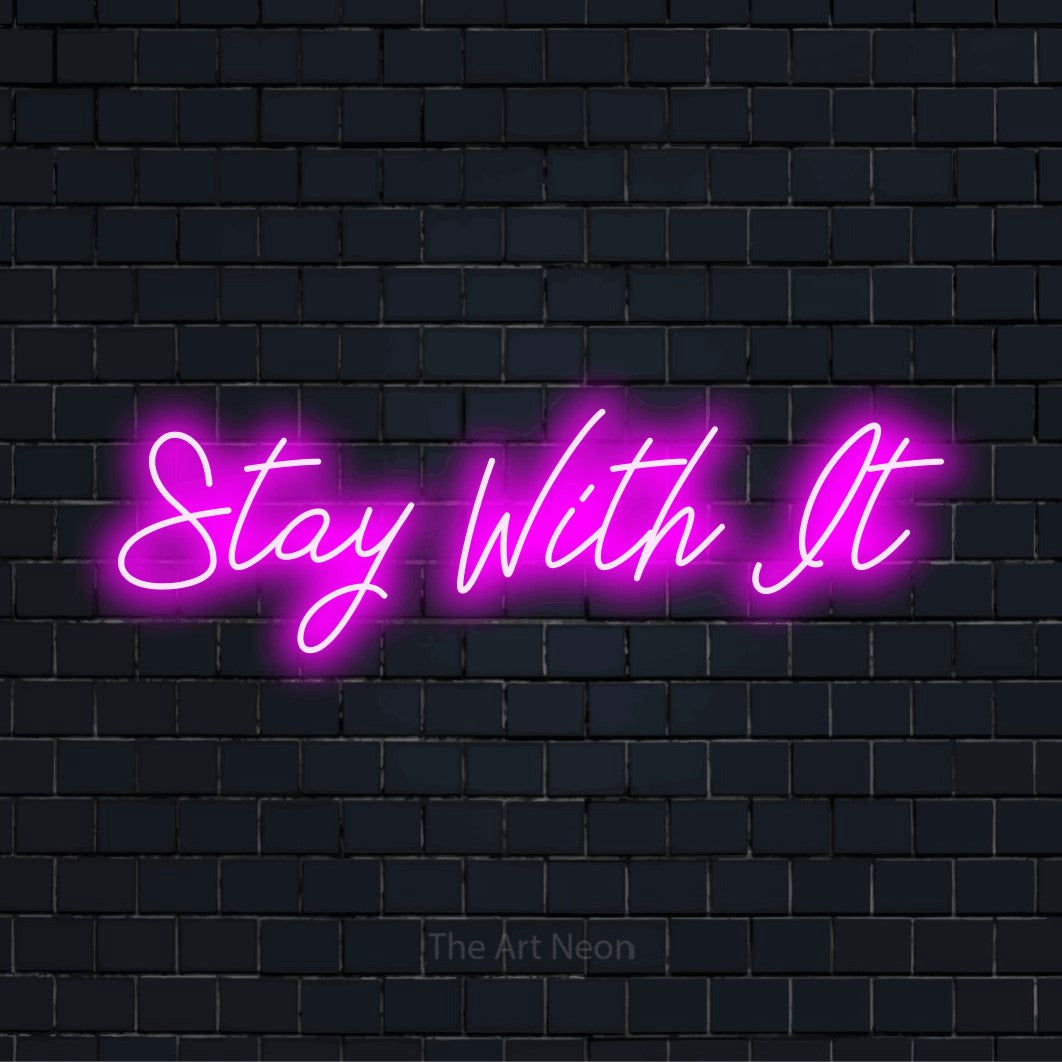 "Stay With It" neon text design on a black brick wall