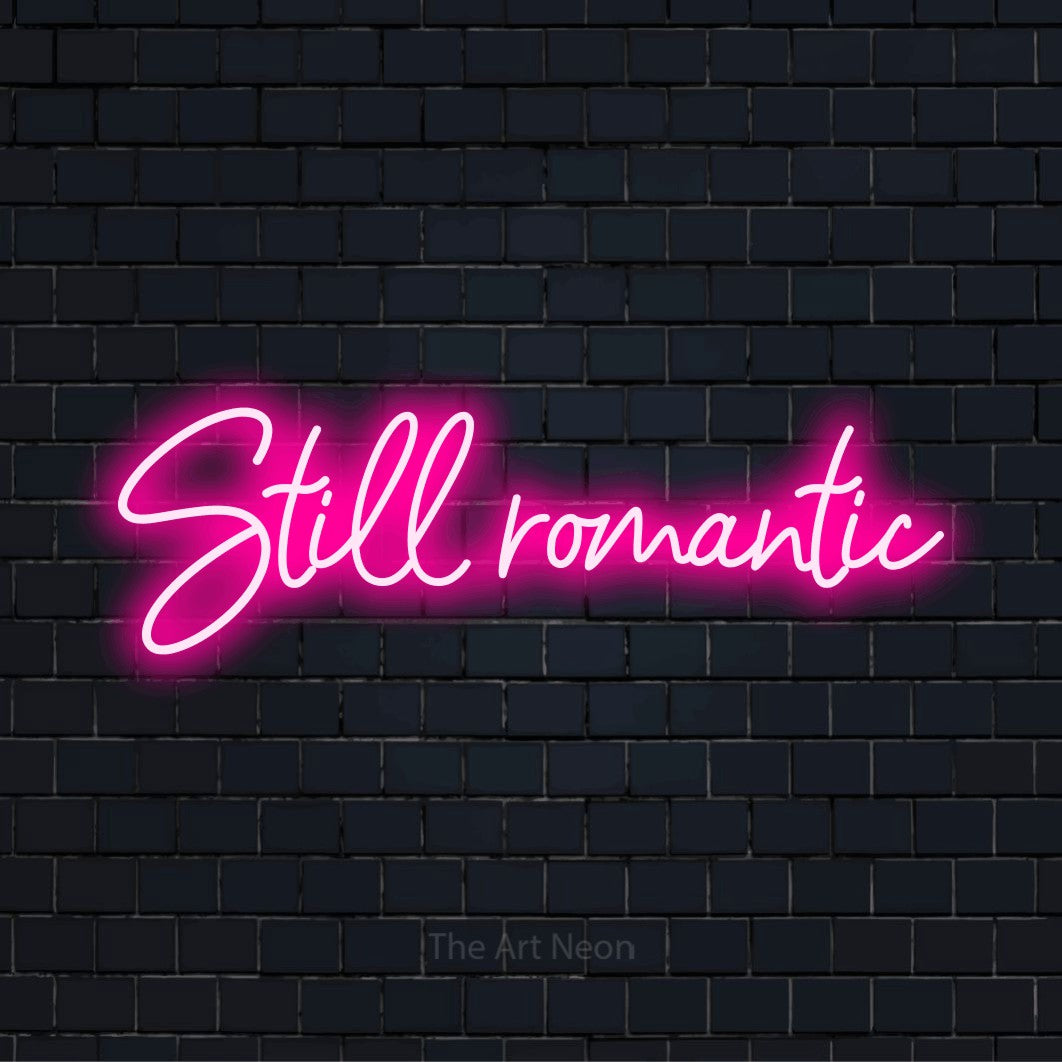 "Still Romantic" LED neon sign on a black brick wall