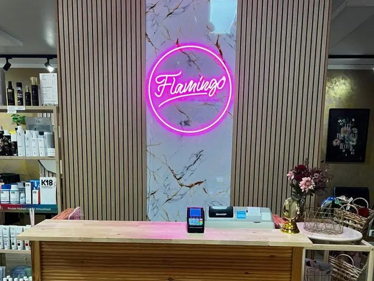 Pink Flamingo logo neon sign installed behind the reception desk at Parturi-Kampaamo Flamingo