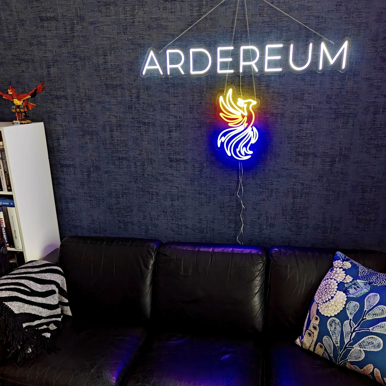 White ARDEREUM office logo LED neon installed on a dark textured wall.