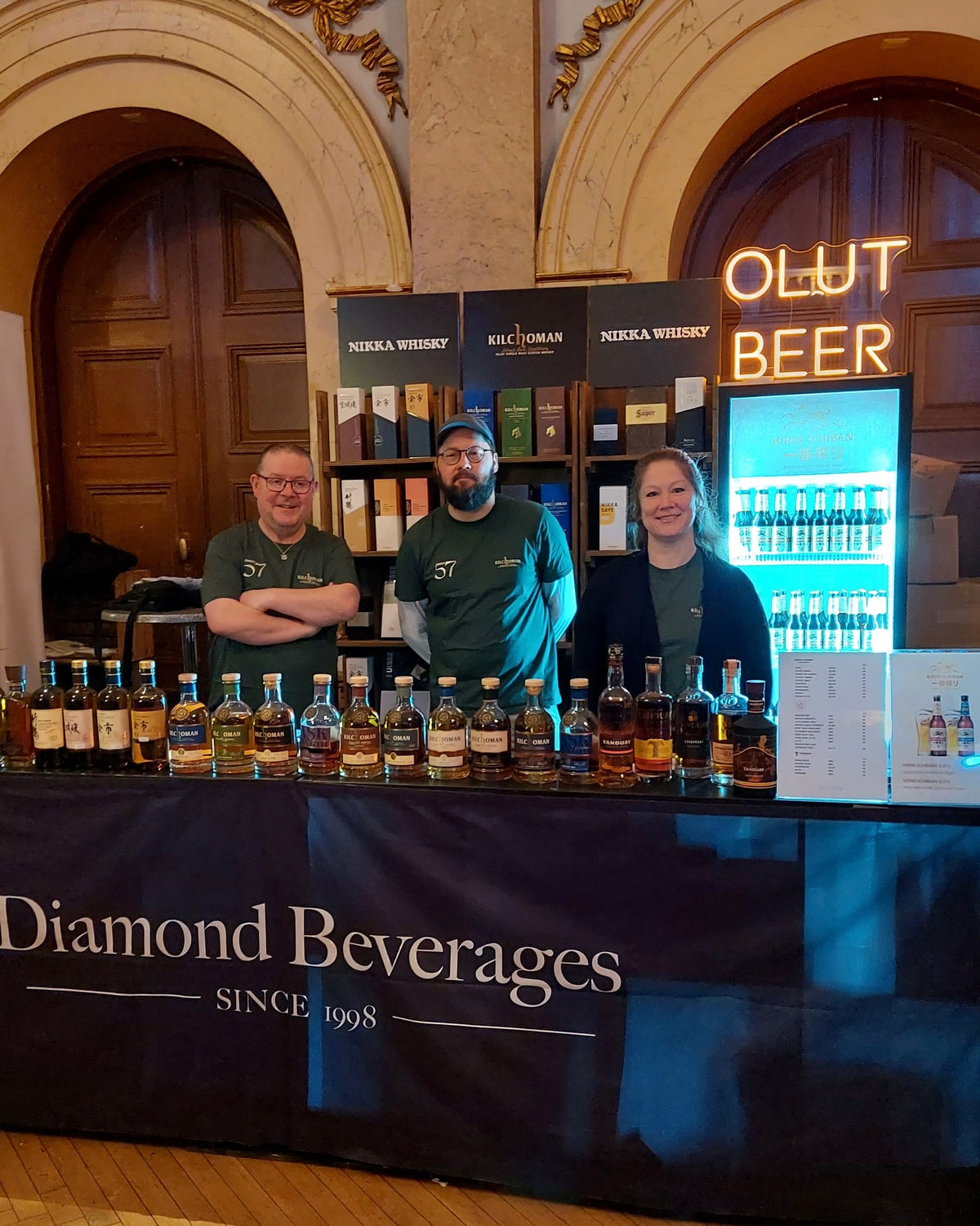 Warm verlichte OLUT BEER-tekst in LED-neon boven de proefstand van Diamond Beverages.