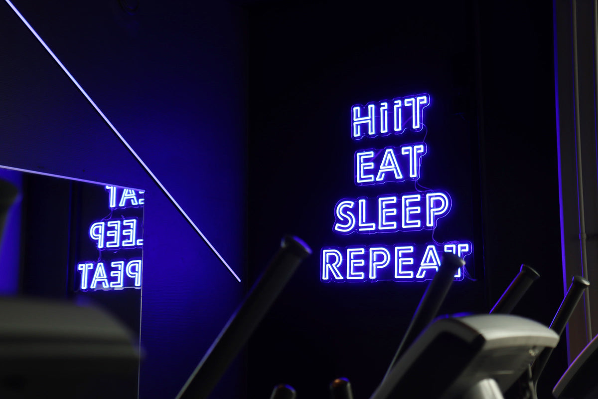 Blue HIIT EAT SLEEP REPEAT LED neon sign mounted inside Kuntomaailma gym in Jyväskylä