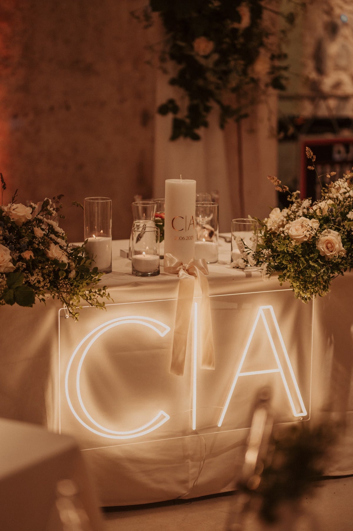 De initialen C en A in warmwit LED-neon op een tafel tijdens een huwelijksfeest.