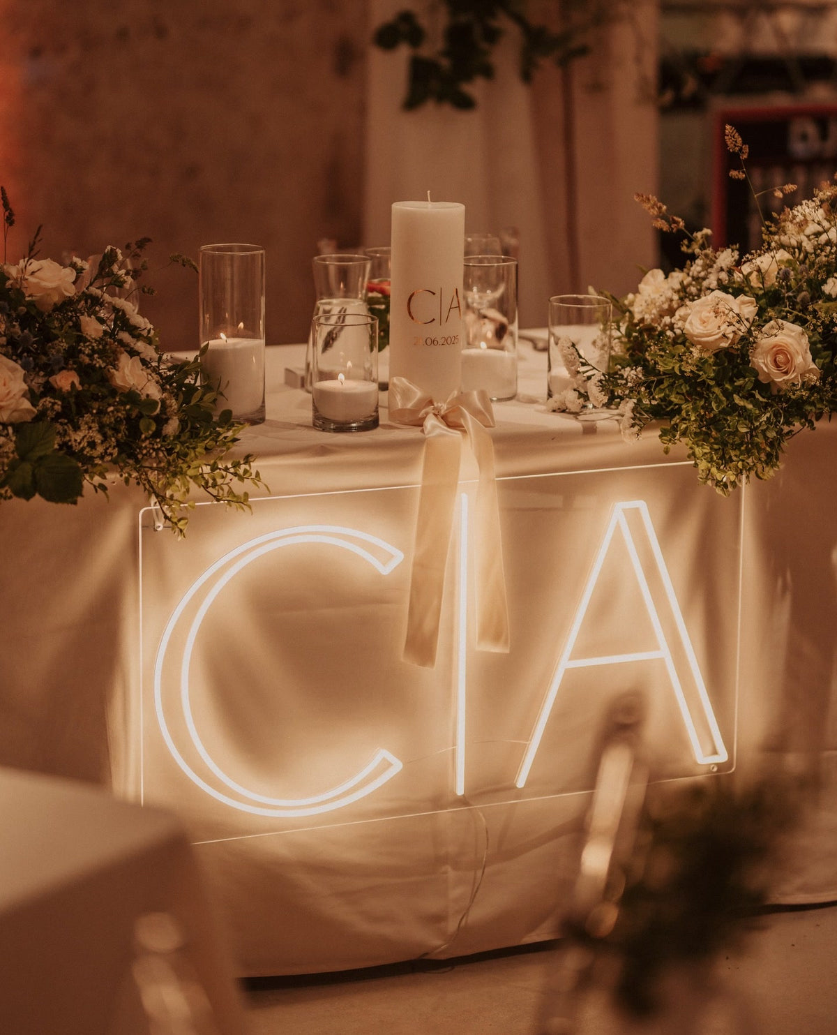 De initialen C en A in warmwit LED-neon op een tafel tijdens een huwelijksfeest.