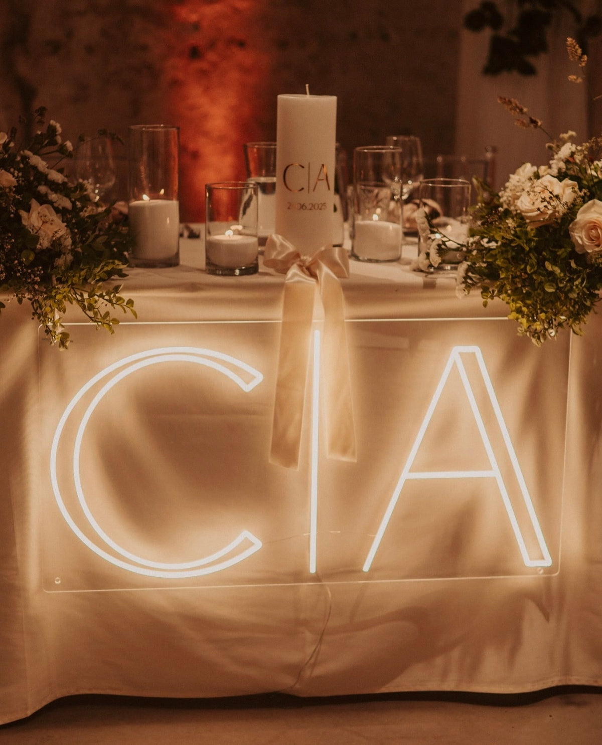 De initialen C en A in warmwit LED-neon op een tafel tijdens een huwelijksfeest.