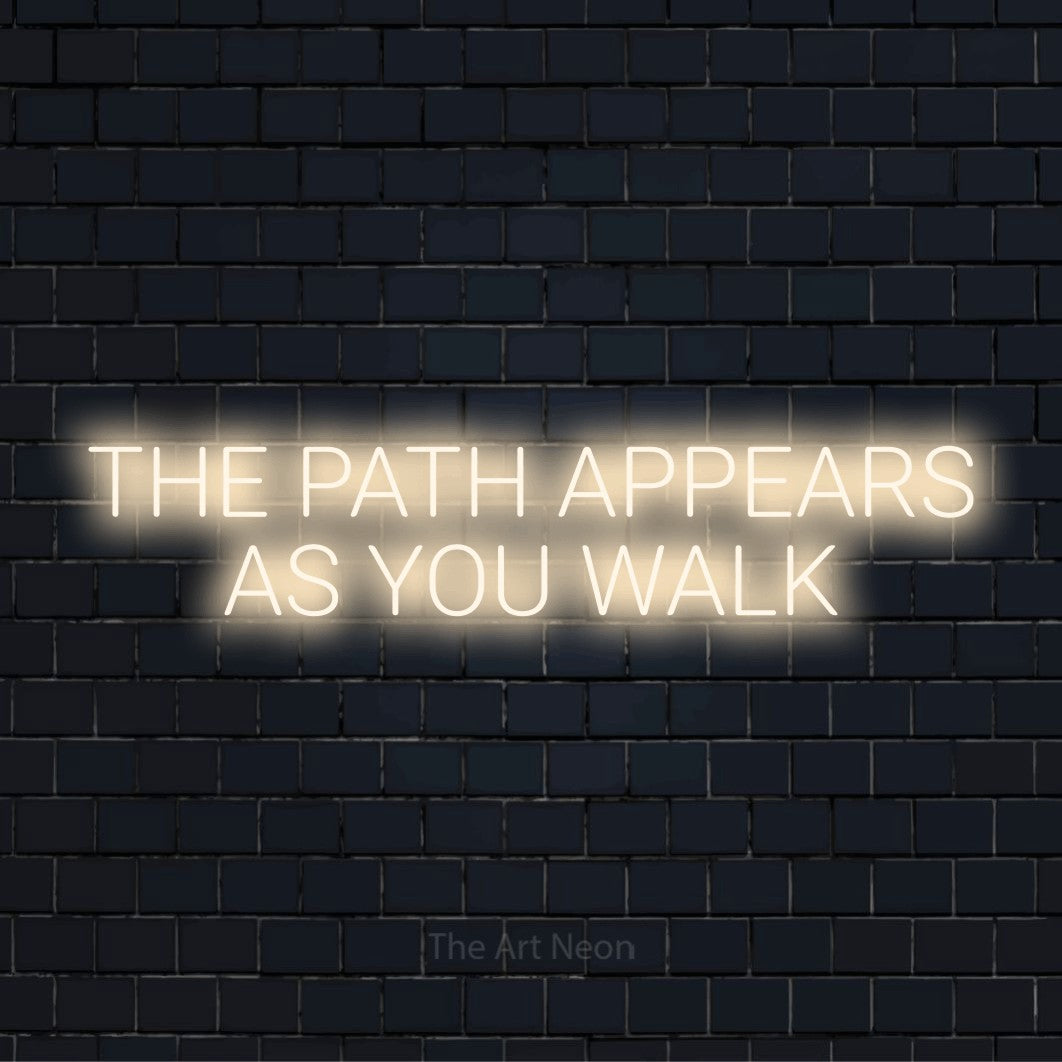 "The Path Appears As You Walk" script-style LED neon sign on a black brick wall