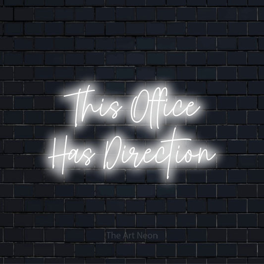 "This Office Has Direction" glowing LED neon sign on a black brick wall