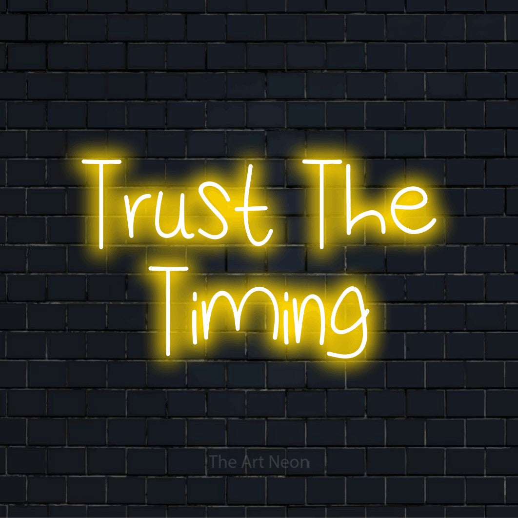 "Trust The Timing" neon text design on a black brick wall