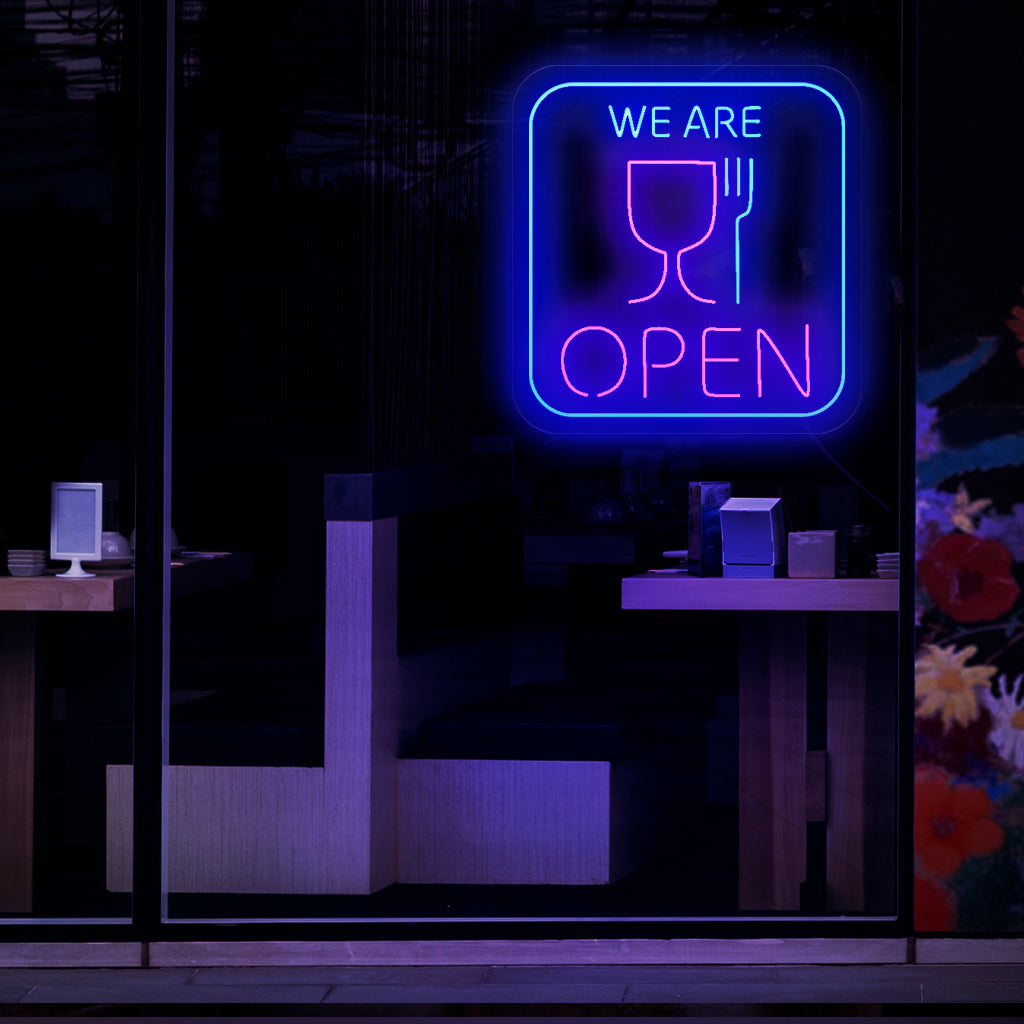 Een opvallend neonbord met de symbolen van een kopje en een vork, dat aangeeft dat een restaurant of eetgelegenheid geopend is.