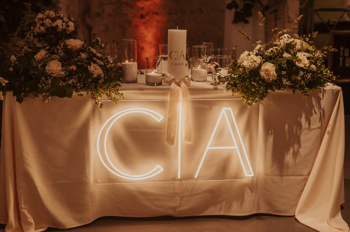 Custom initials LED neon sign styled with flowers and candles at a wedding reception
